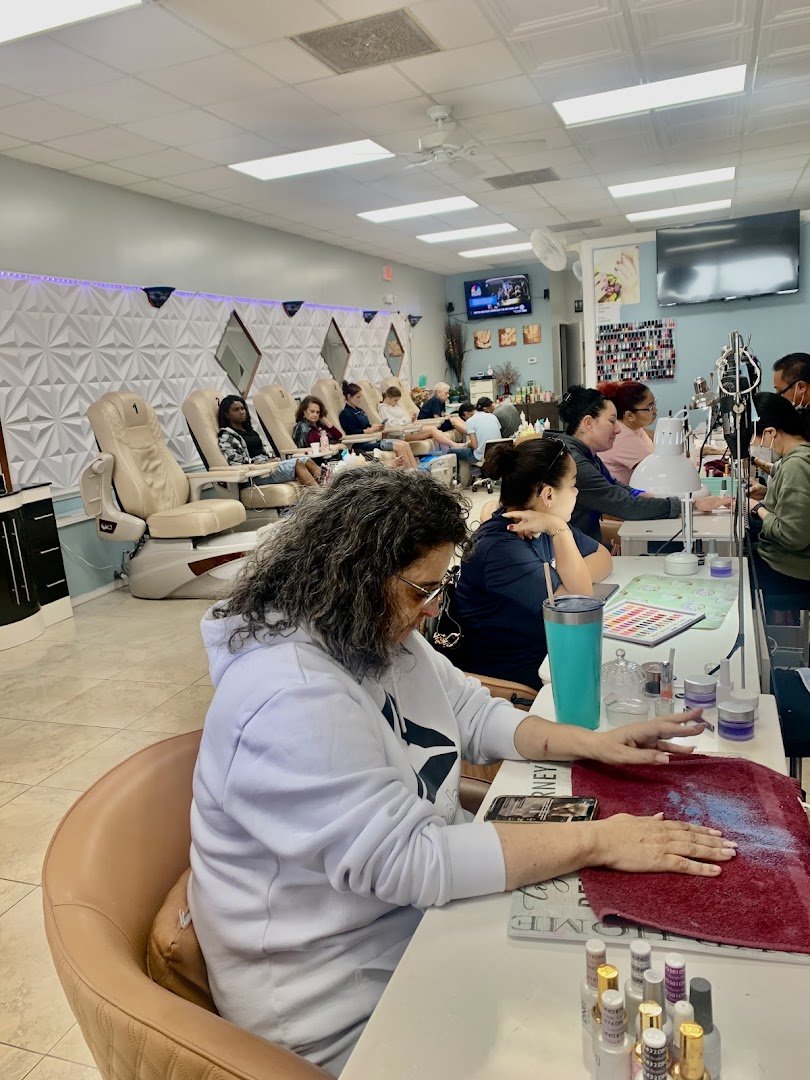 Nail technician shaping acrylic nails at a salon table
