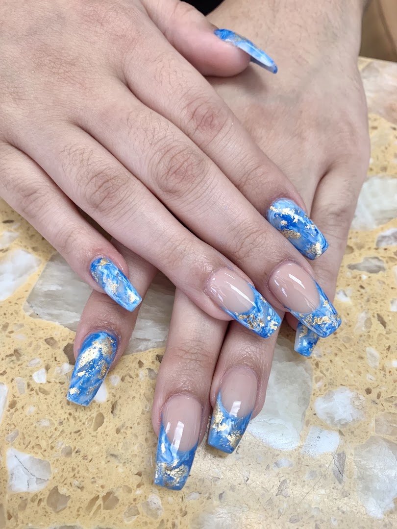 Nail technician shaping acrylic nails at a salon table